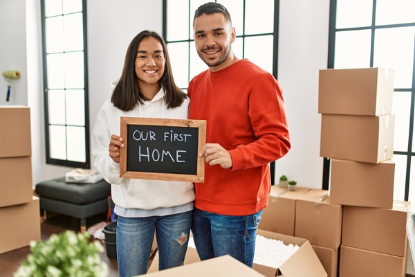 Young latin couple smiling happy holding blackboard with our first home message.