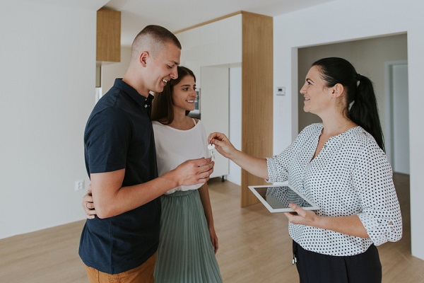 Smiling Agent Giving House Key To Couple Standing At Home, Paint color of year